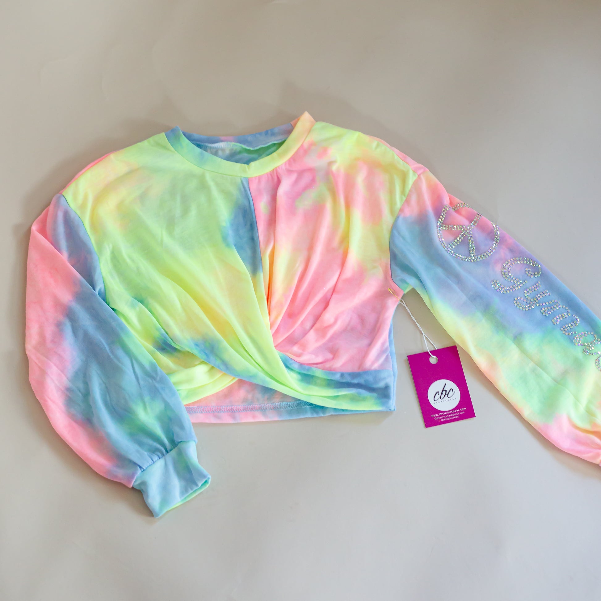 Colorful tie-dye long sleeve crop top by cbcsportswear with 'Gymnast' and peace sign text on sleeve. Made from light, comfortable fabric. Perfect for young gymnasts for practice or casual wear